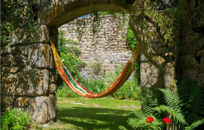 Hamac tendu sous une arche de pierre dans le jardin