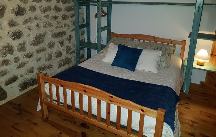 Chambre avec lit double et mur en pierre